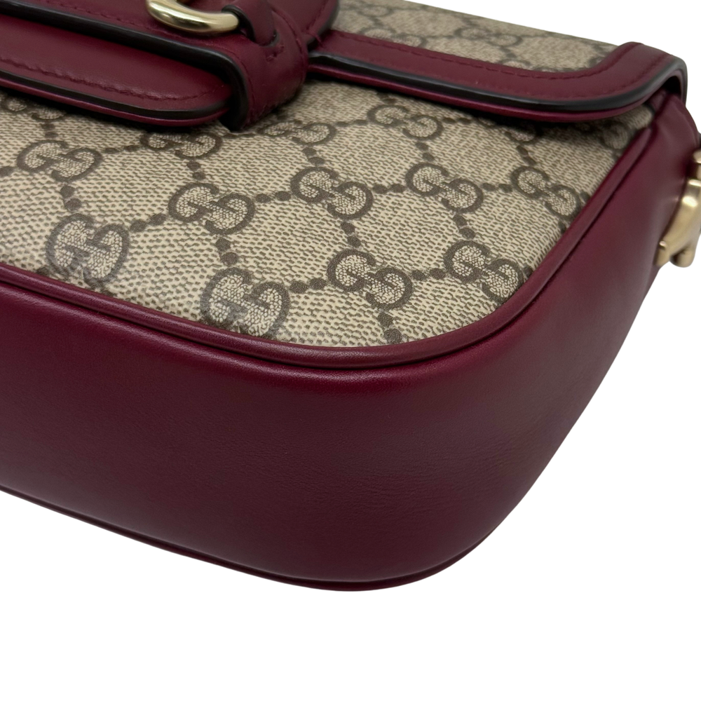 Gucci GG crossbody bag close-up: burgundy leather base and patterned canvas top