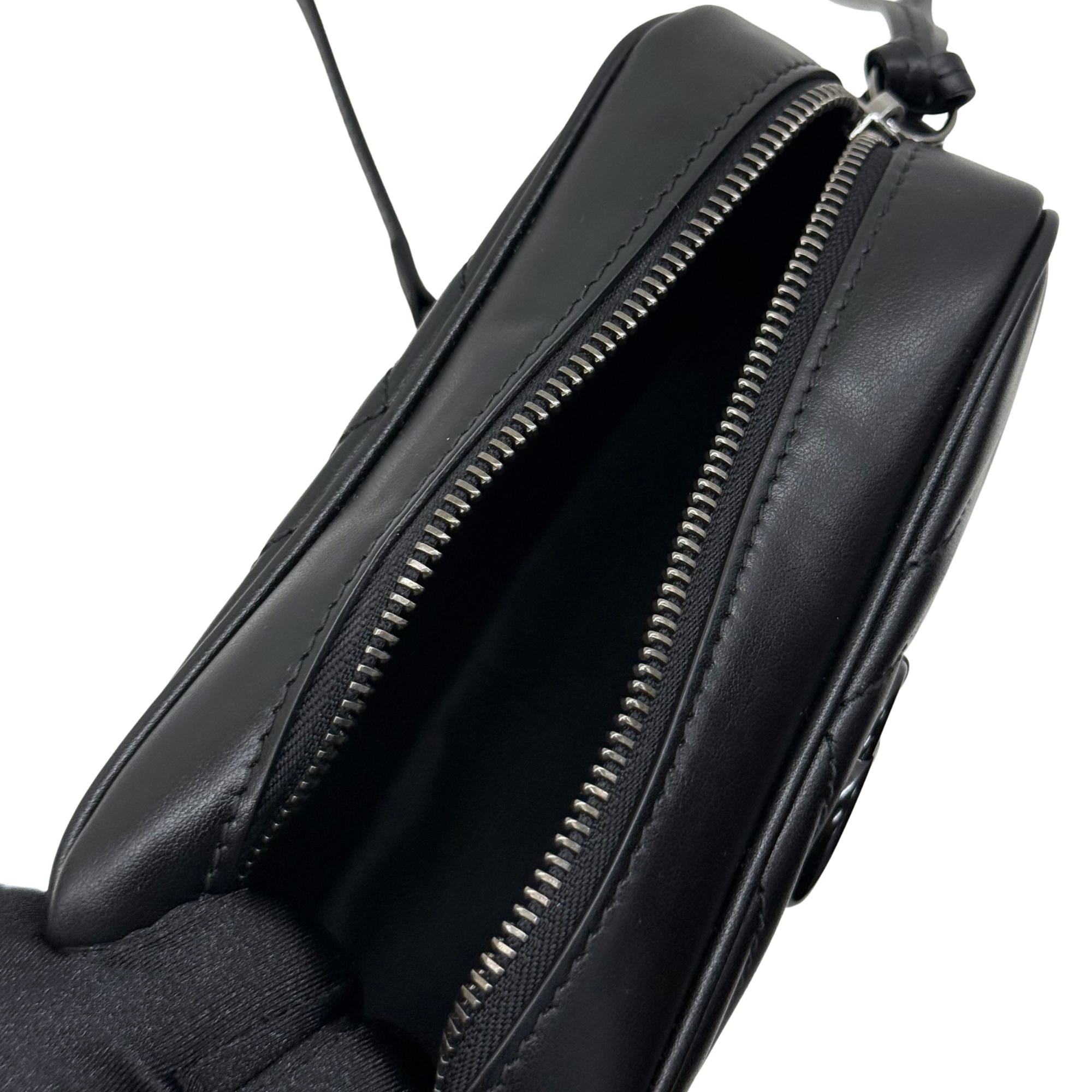 Black leather crossbody bag with two zippers and curved top edge, side view.