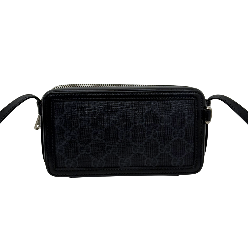 Small crossbody bag front view, dark GG monogram panel, top zip closure