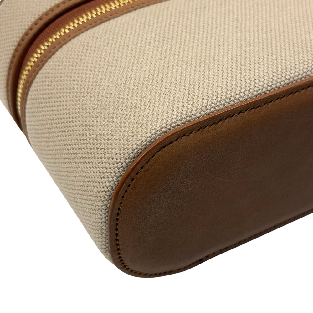 Beige textured canvas with brown leather edge trim and gold zipper detail.