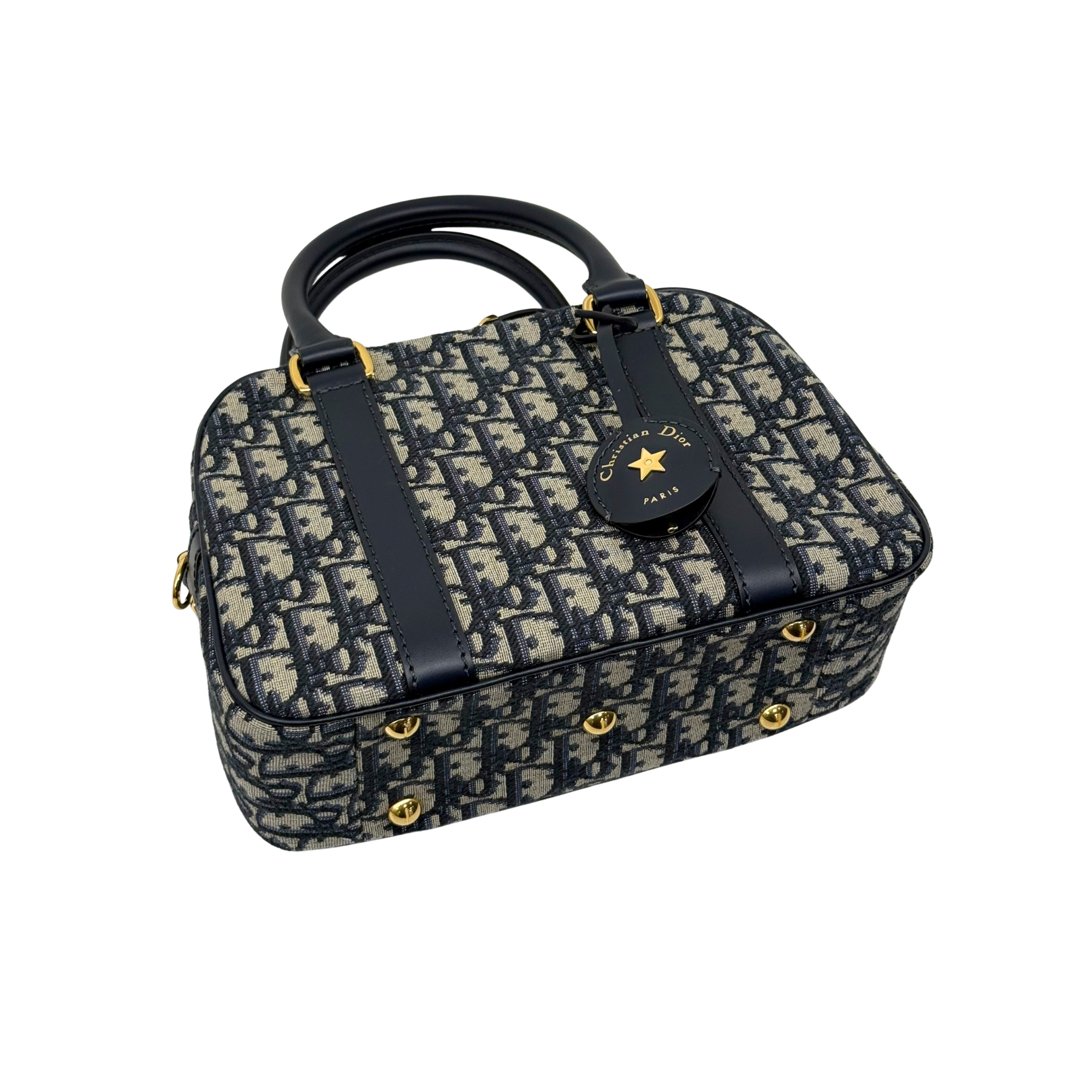 Navy and cream monogram handbag with top handles, front badge charm, and gold hardware