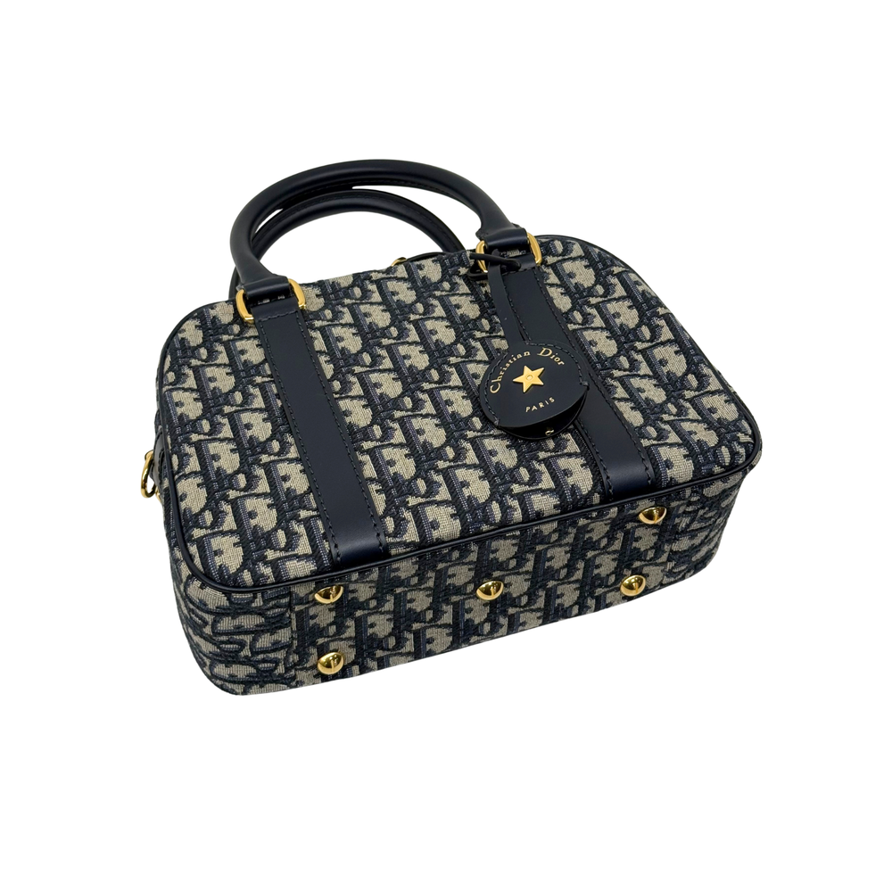 Navy and cream monogram handbag with top handles, front badge charm, and gold hardware