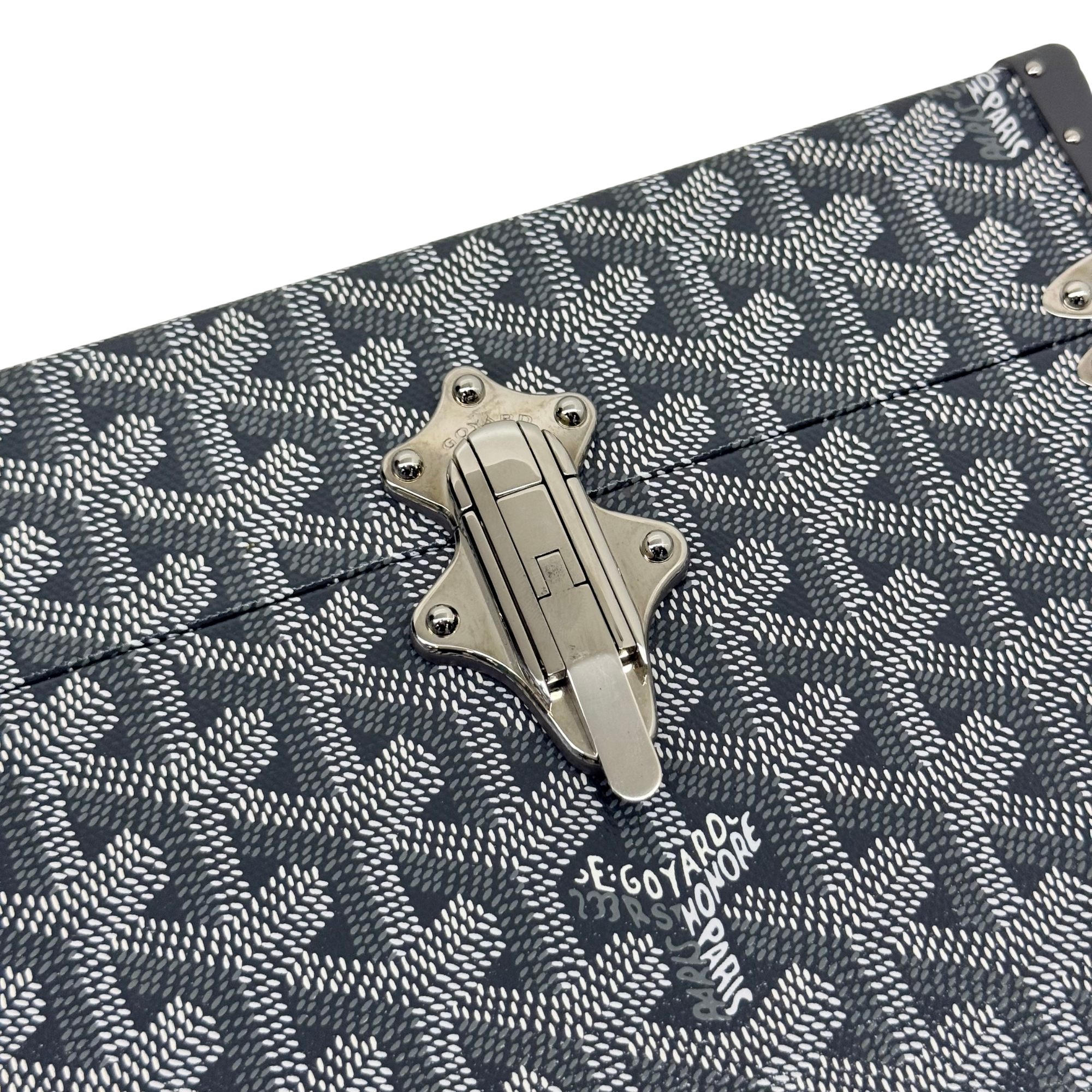 Goyard trunk front hardware latch on dark patterned fabric with repeating motif