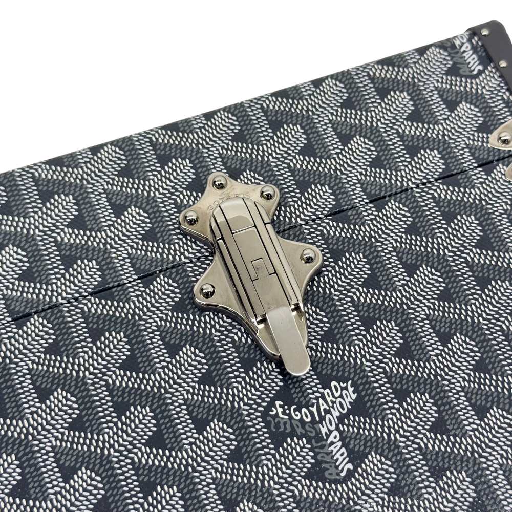 Goyard trunk front hardware latch on dark patterned fabric with repeating motif