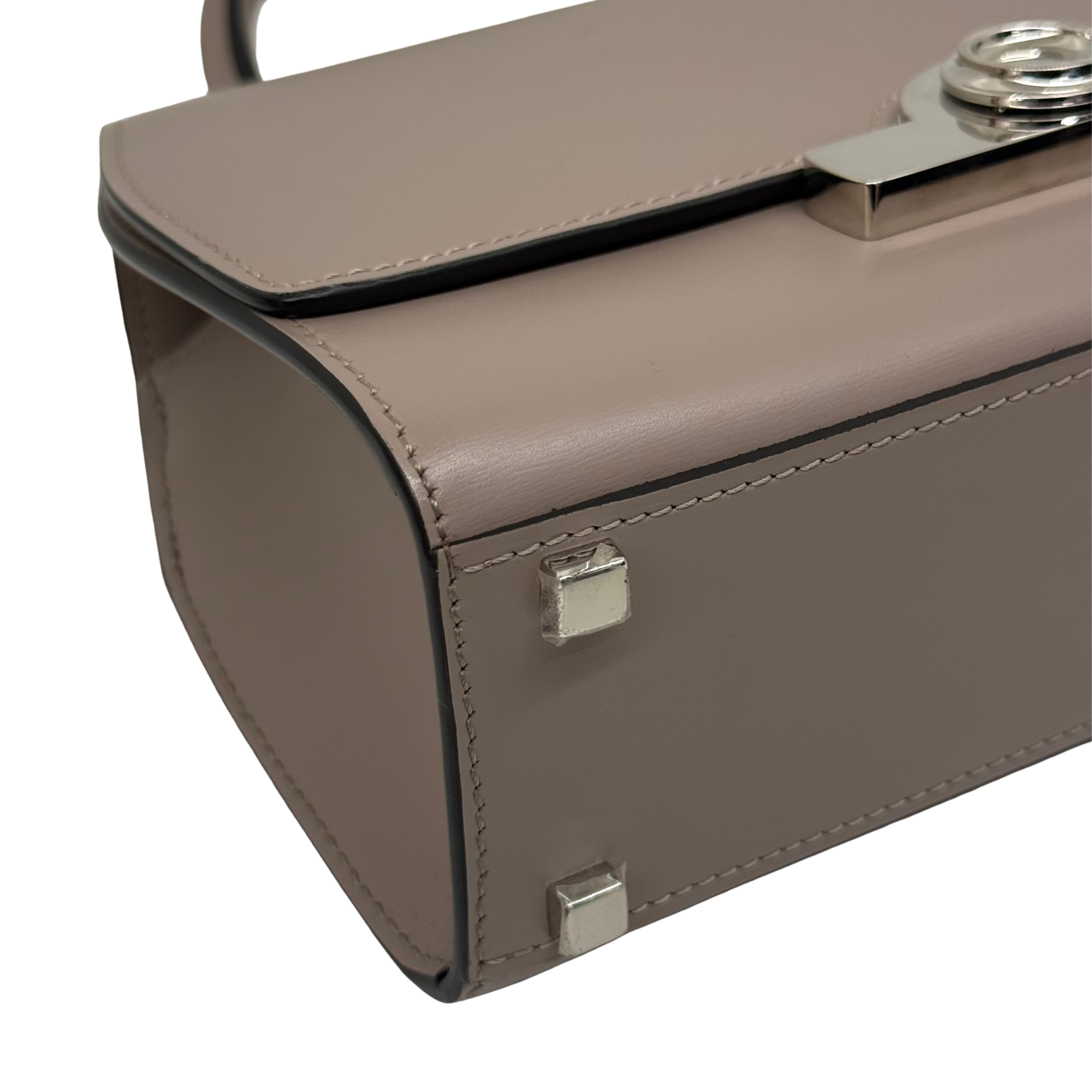 Moynat taupe leather handbag close-up of front flap hardware and corner locks