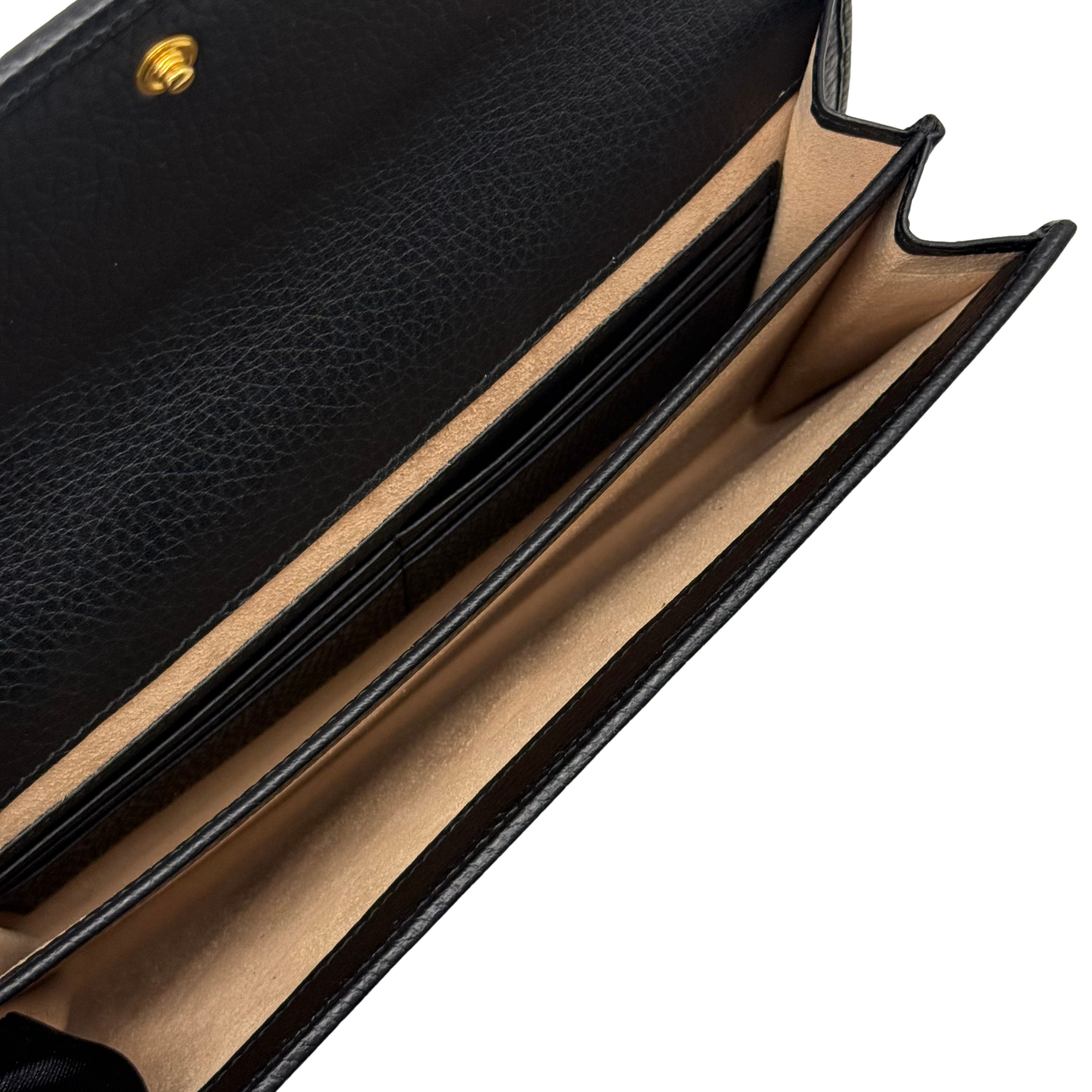 Black leather wallet opening with beige lining and card compartment edges