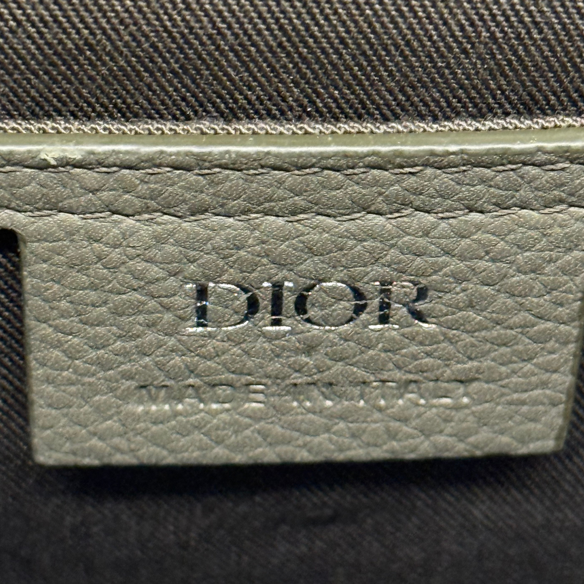 Dior logo patch on light olive leather tab with stitched edge