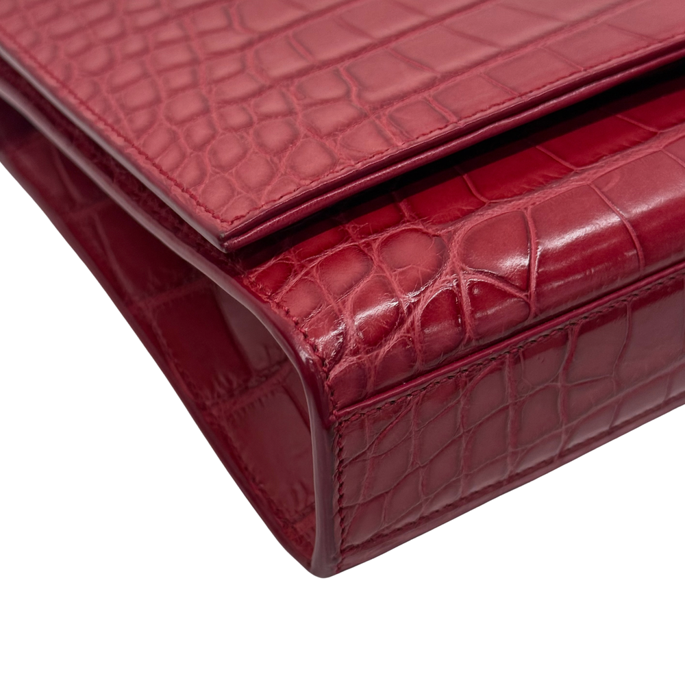 Red croc-embossed clutch corner with glossy finish and structured flap edge