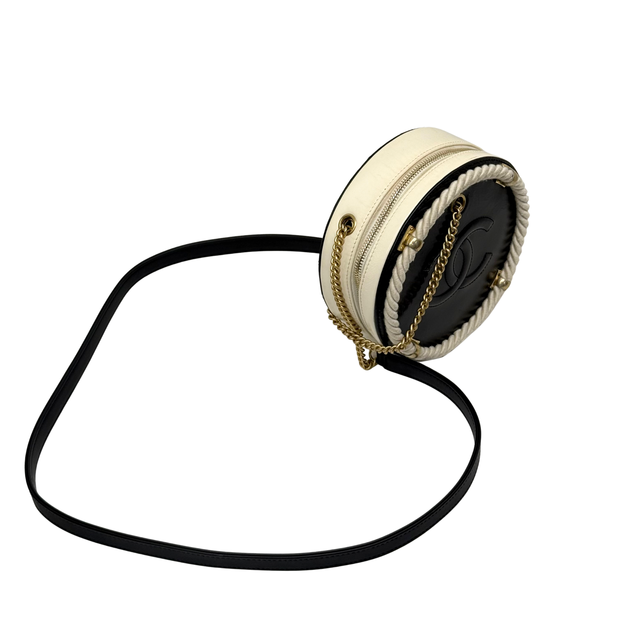 Round Chanel mini crossbody bag with cream exterior, black interior, gold chain strap.