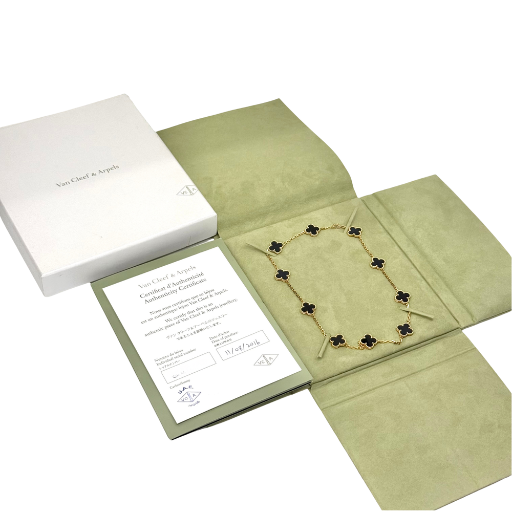 Van Cleef clover necklace on folded paper with gold-tone chain and black motifs