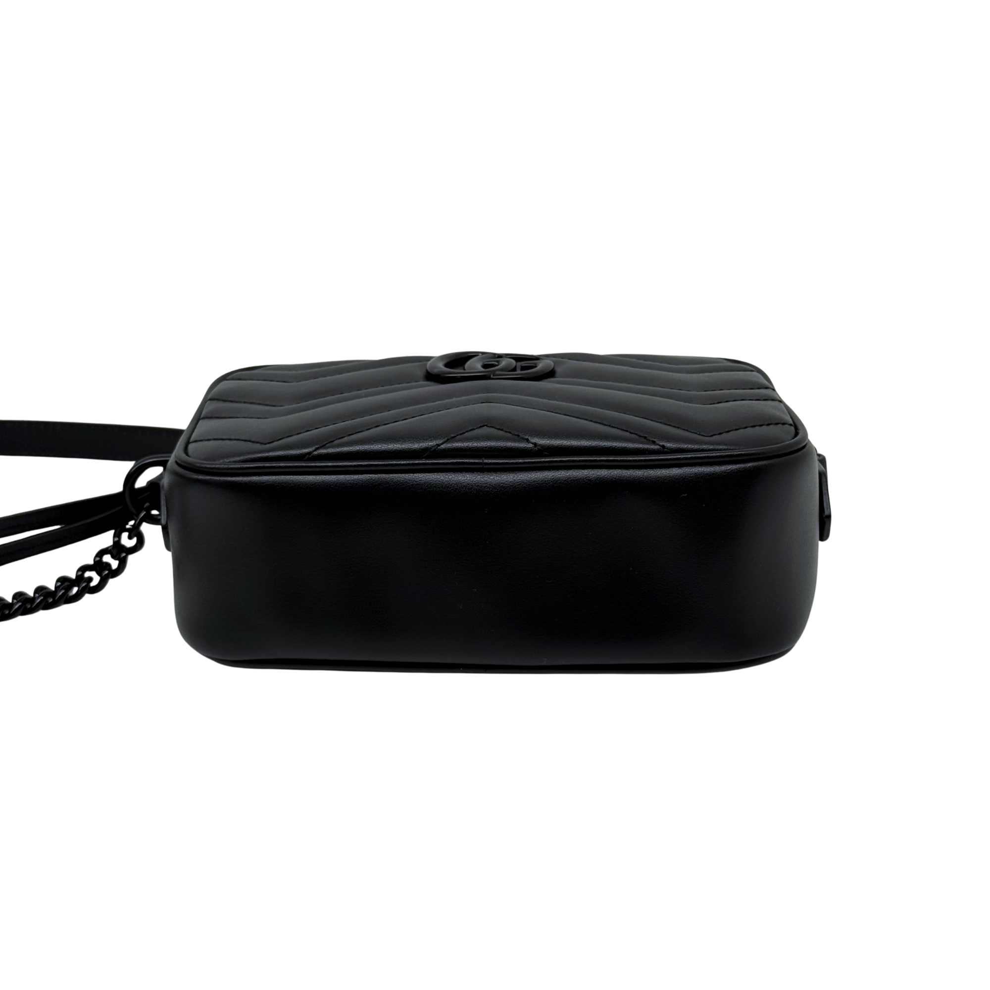 Black quilted leather crossbody bag with circular logo on top, back view.