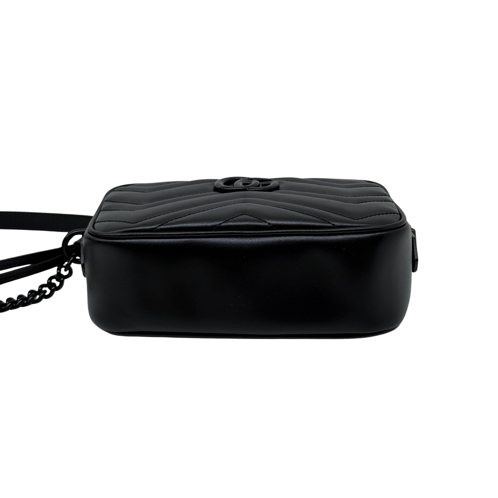 Black quilted leather crossbody bag with circular logo on top, back view.