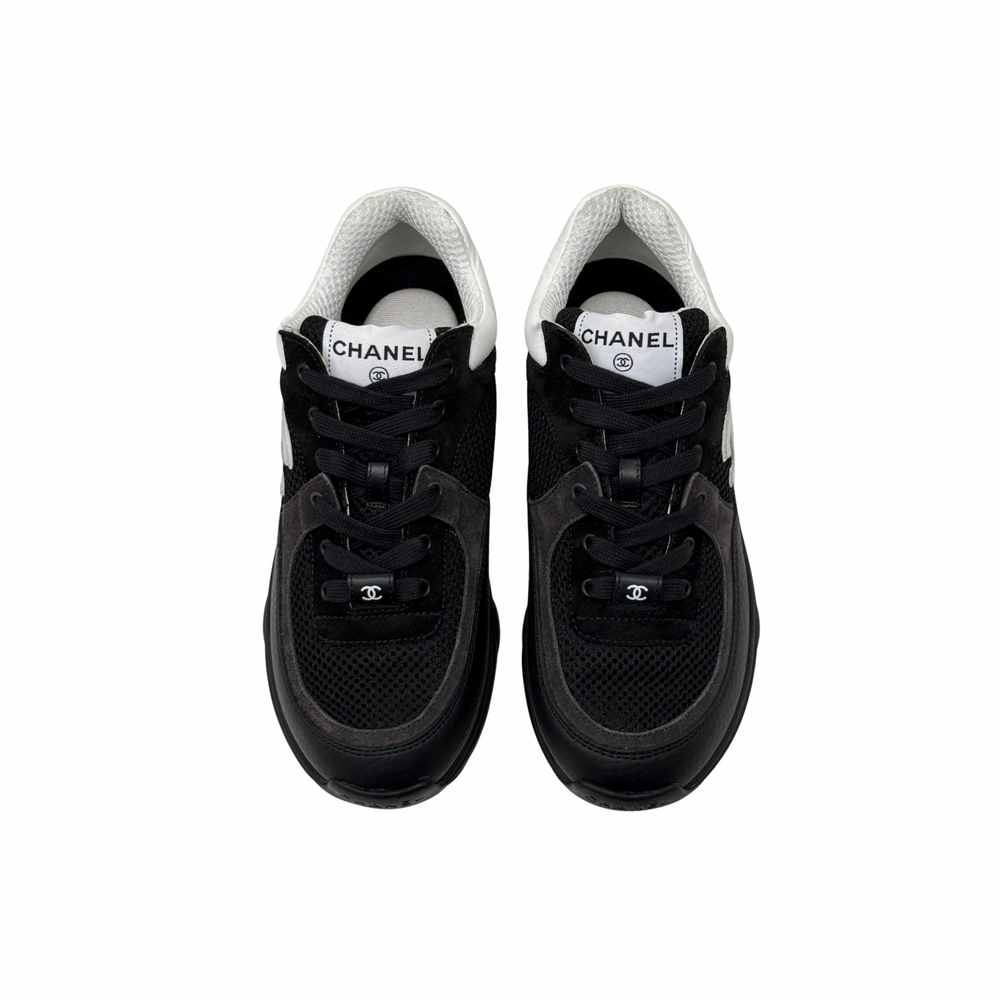 Black low-top sneakers with white collars and lace-up front, padded tongue.
