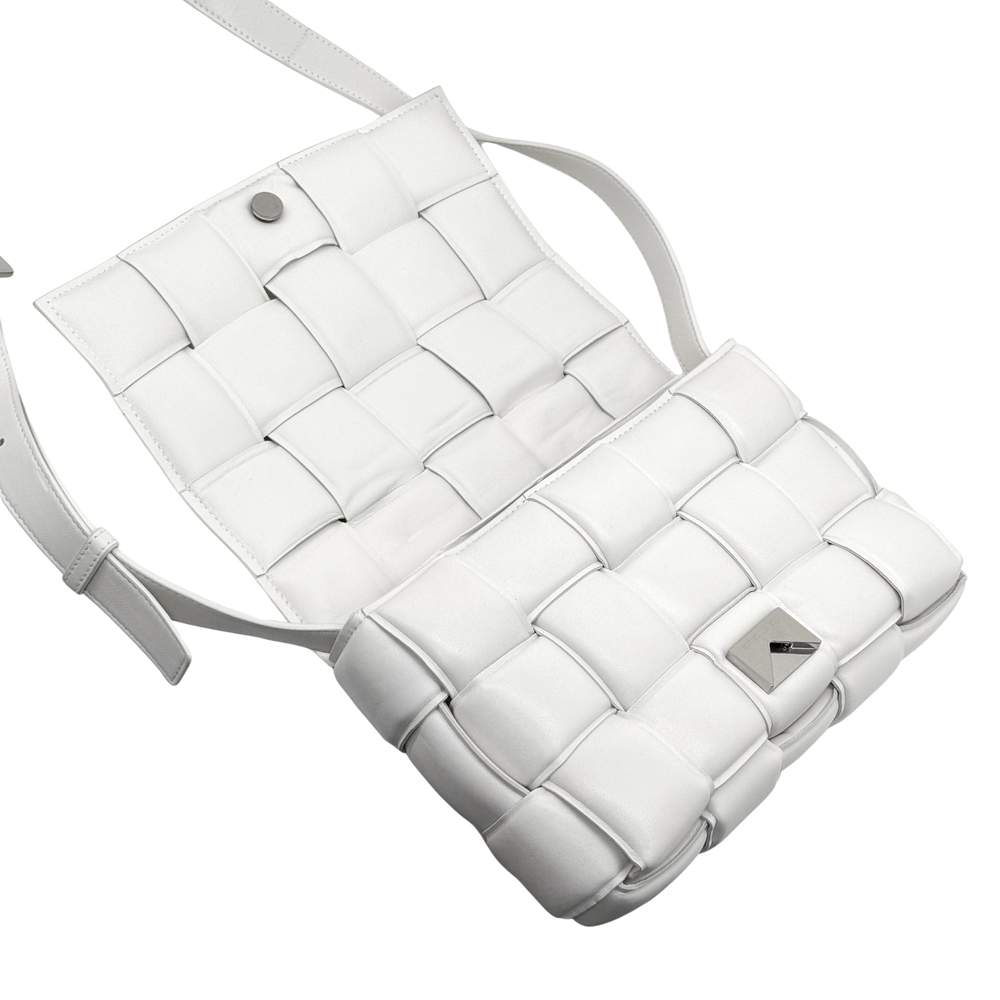 White leather crossbody bag with woven-style exterior, snap tab, and crossbody strap