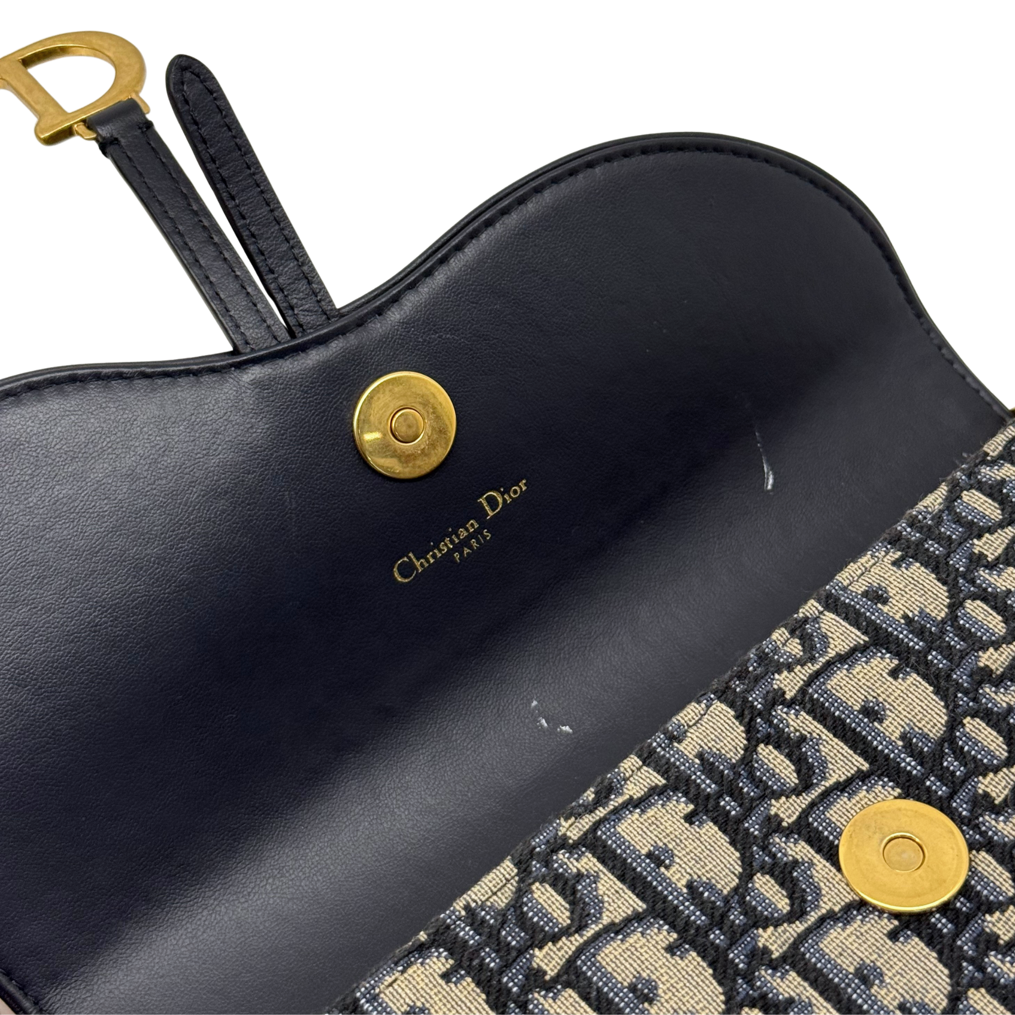 Dior crossbody bag front with black leather panel, logo stamp, and gold snap hardware