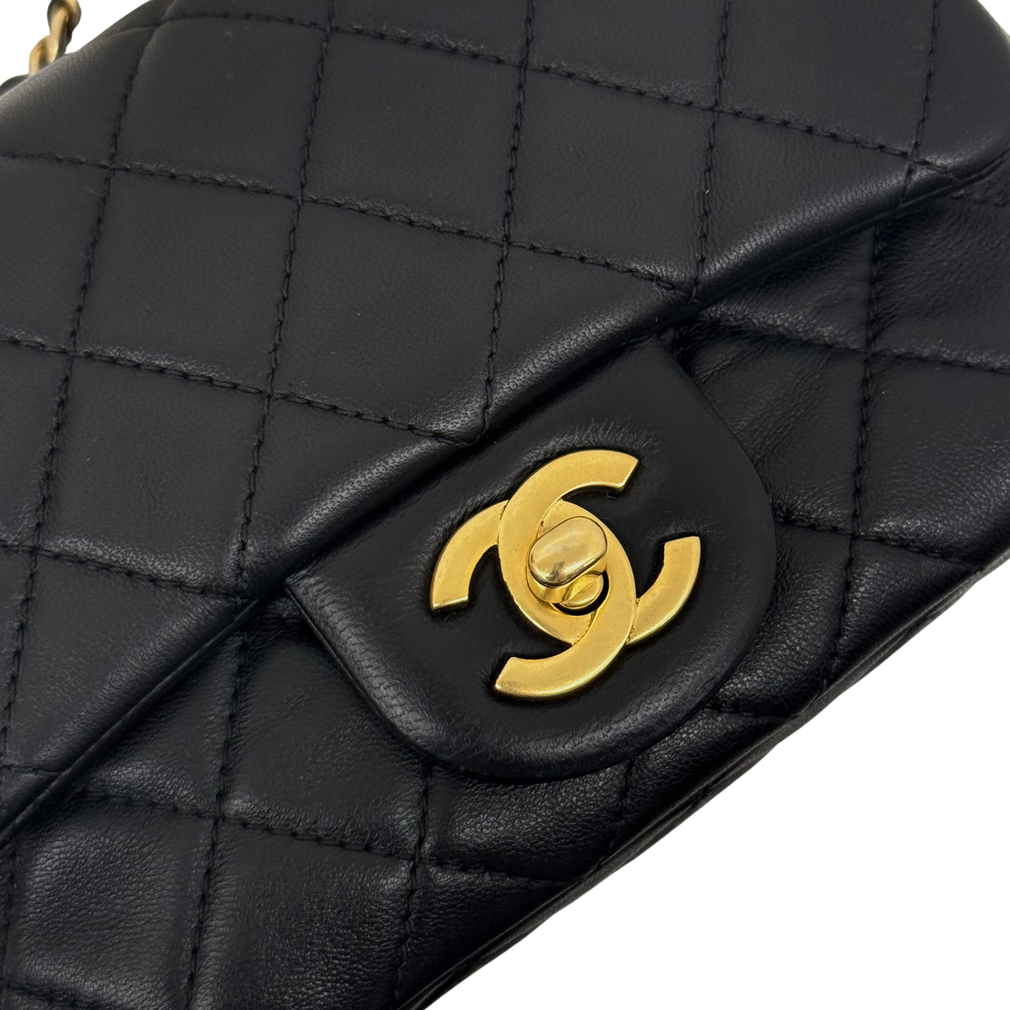 Pre-owned quilted shoulder bag close-up of gold “5” emblem on black leather flap