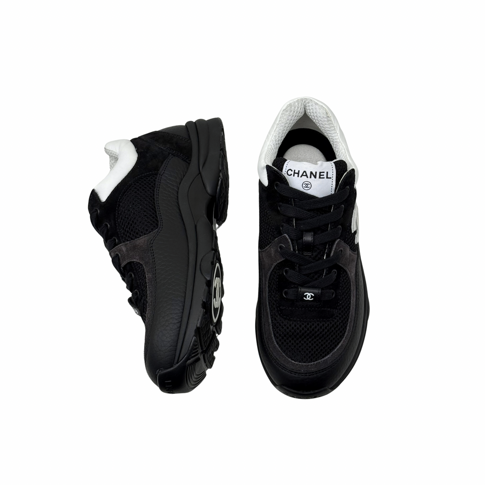 Black low-top sneakers with white collar, lace-up front, chunky rubber sole.