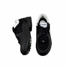 Black low-top sneakers with white collar, lace-up front, chunky rubber sole.