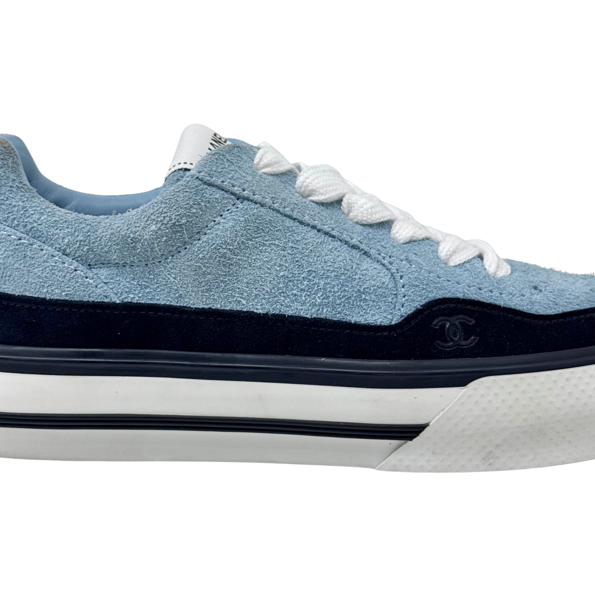 Blue suede sneaker side profile with small CHANEL emblem on black trim