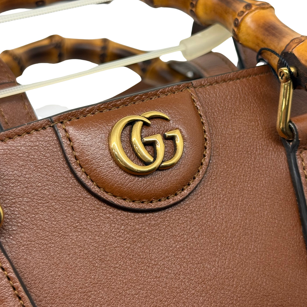 Gold-tone Gucci GG logo plaque on brown leather tote with decorative stitching