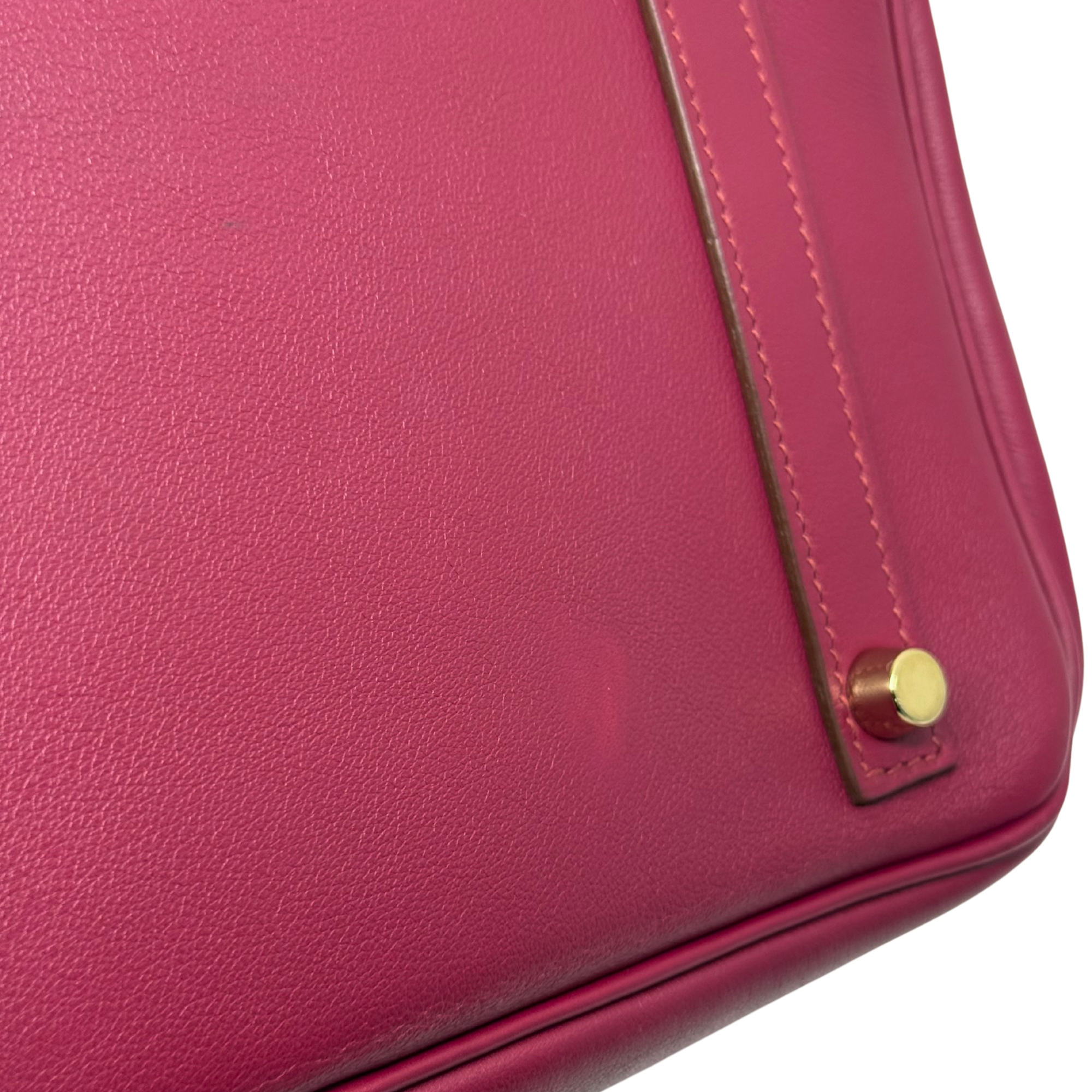 Magenta leather Birkin bag side corner with gold snap stud and stitched edge
