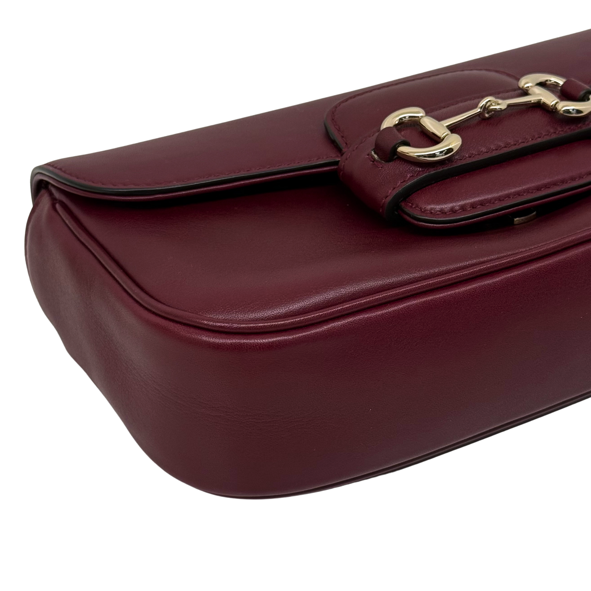 Maroon leather mini bag with gold-tone clasp hardware on top flap