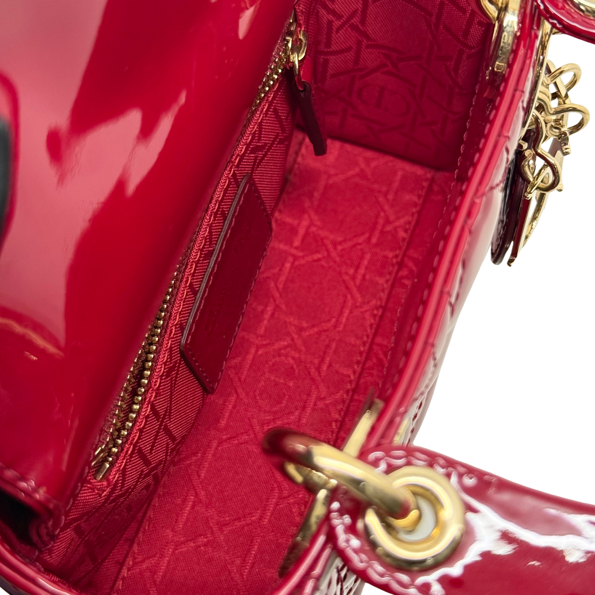 Red quilted patent leather handbag with side zipper, gold hardware, and chain strap