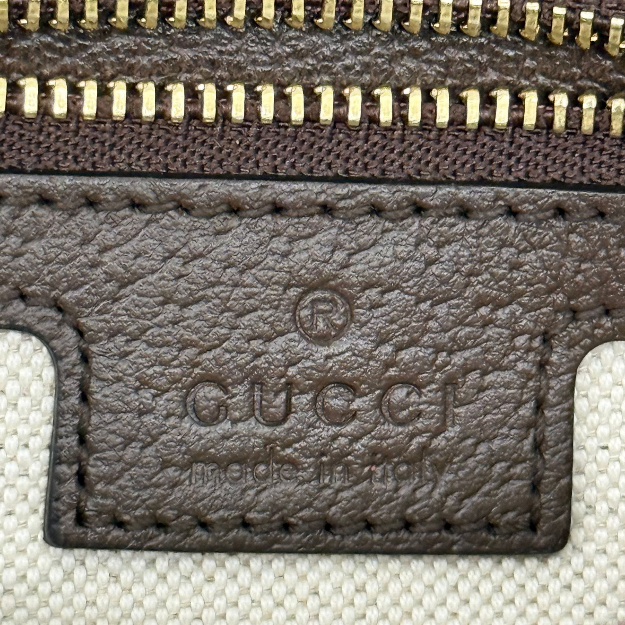 Gucci GG canvas wallet-style pouch with brown leather trim and stitched logo patch