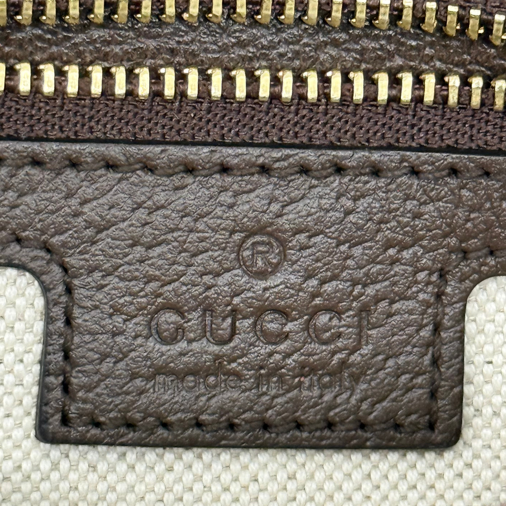 Gucci GG canvas wallet-style pouch with brown leather trim and stitched logo patch