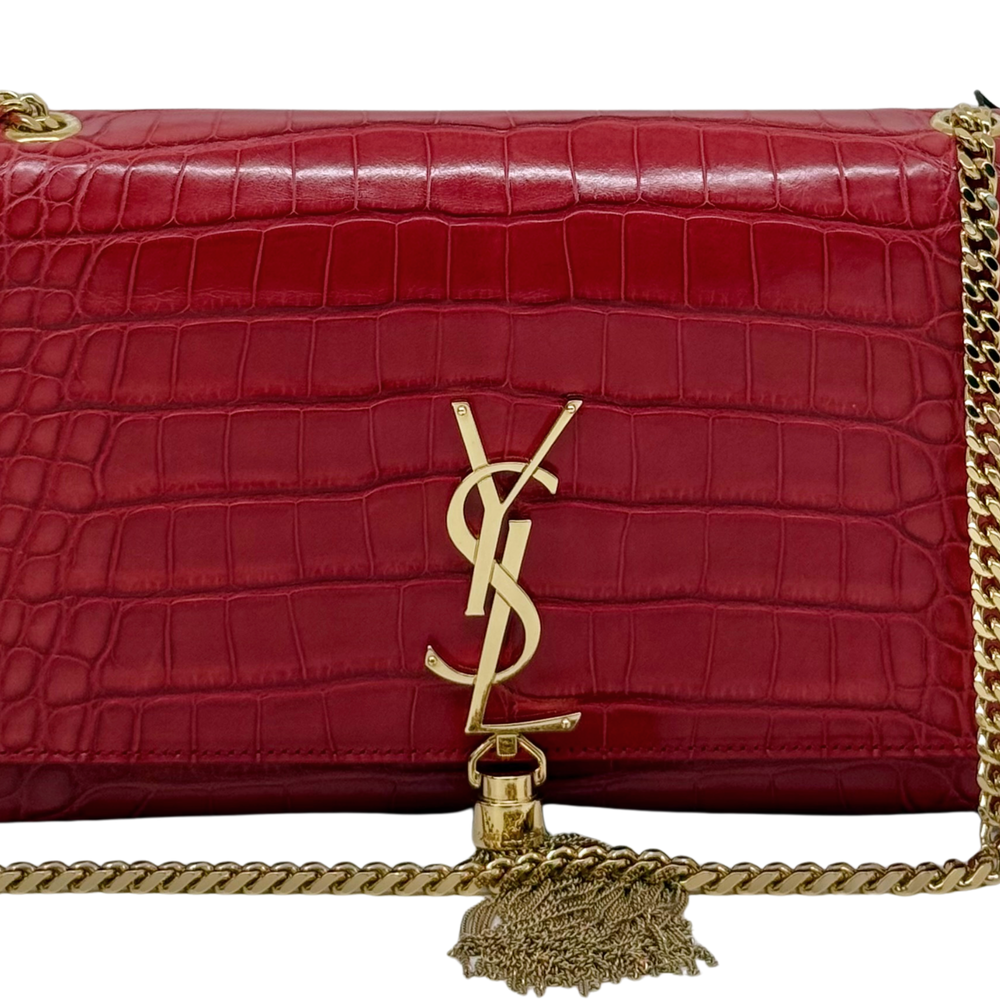 Close-up of red crocodile-embossed leather flap with gold YSL monogram and tassel