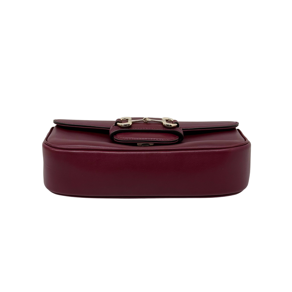Maroon leather mini shoulder bag with front clasp detail on top flap