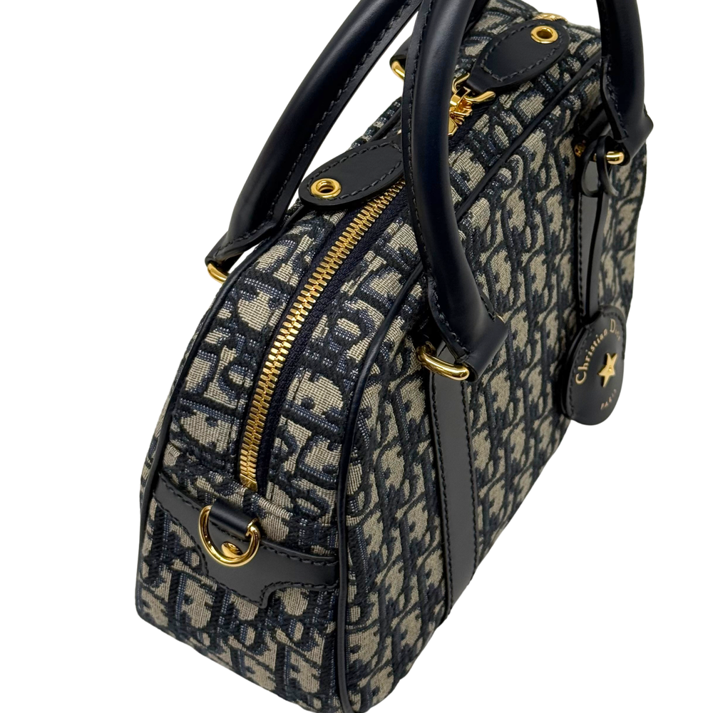 Navy and cream monogram handbag with front zipper, black strap, and gold-tone rings