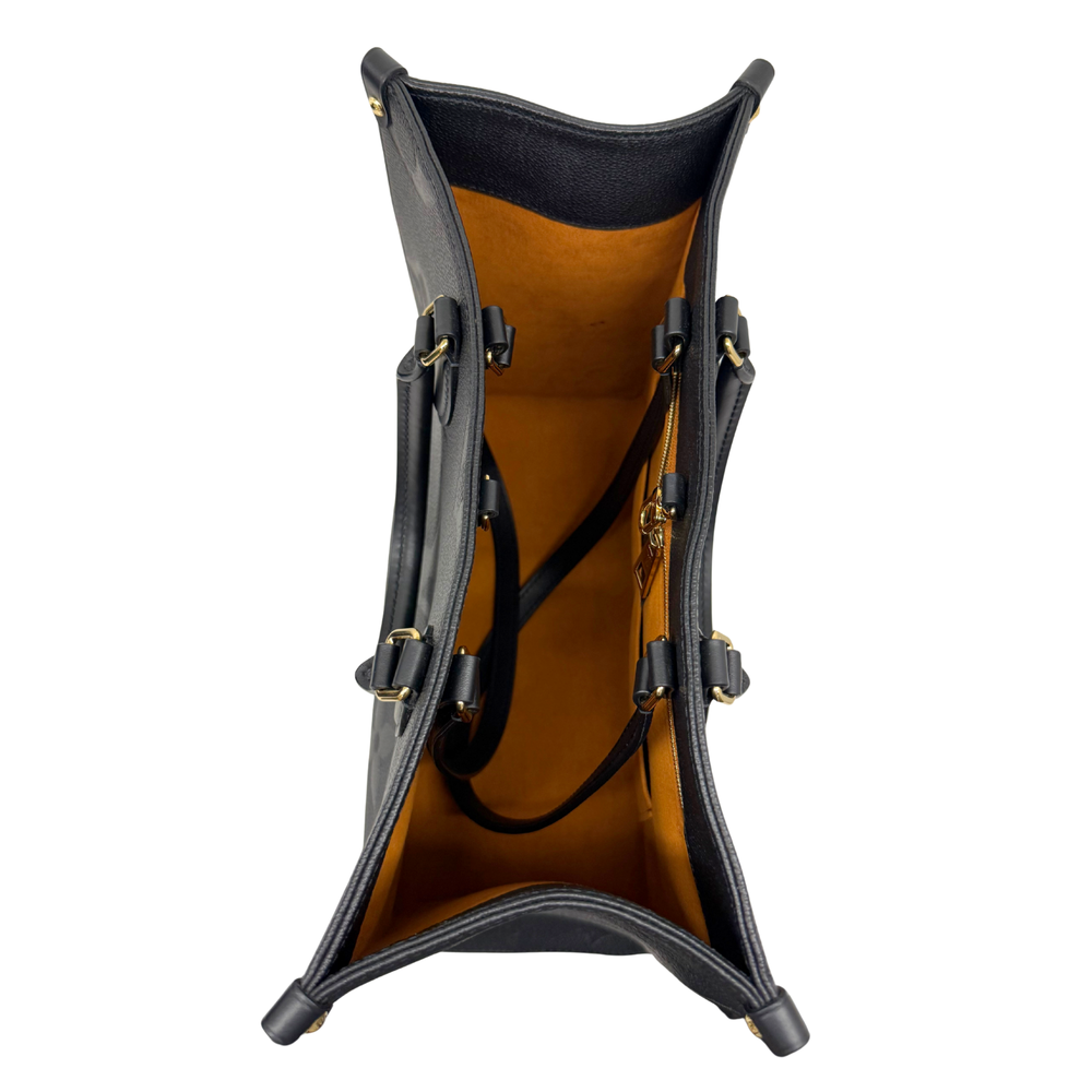 Louis Vuitton tote bag standing upright with black adjustable side straps and hardware