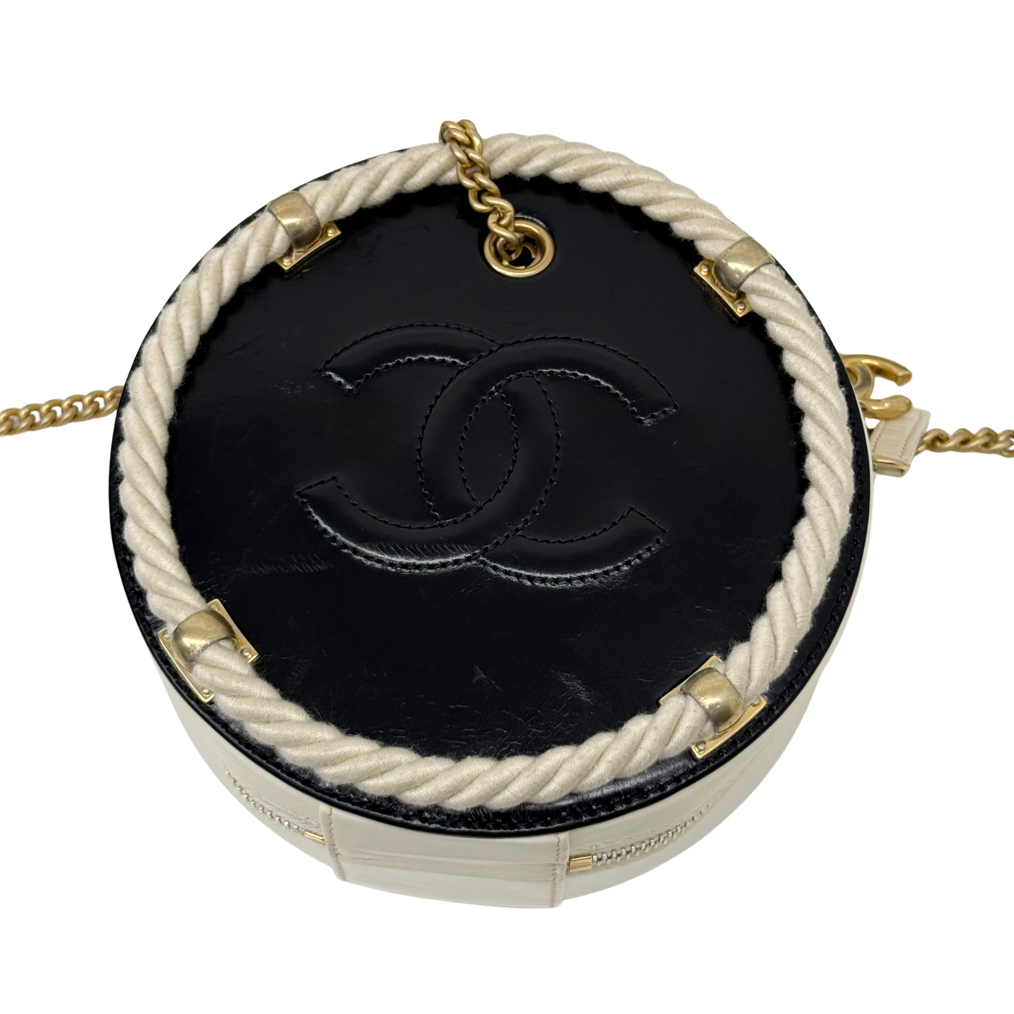 Top view of cream round bag with black leather base, braided rope trim, gold chain