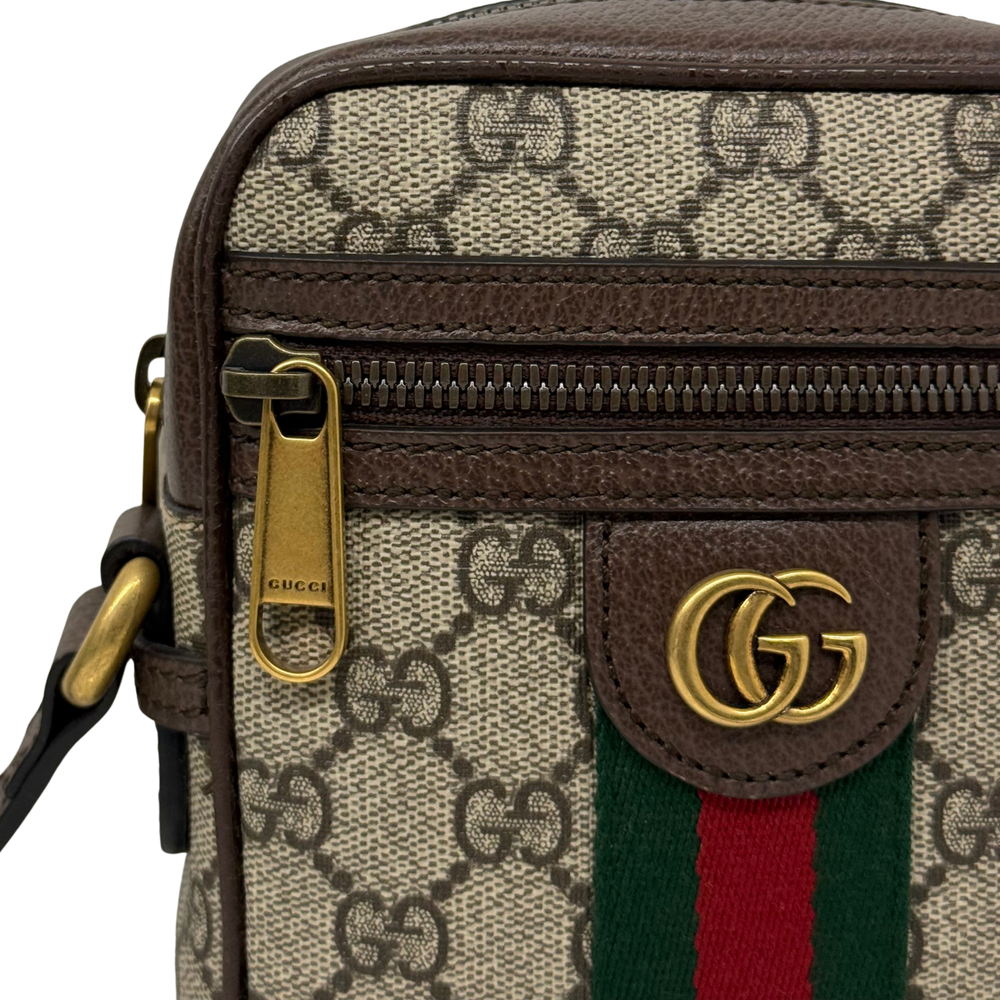 Gucci GG canvas bag front close-up with Gucci logo plaque, web stripe, and zip pocket