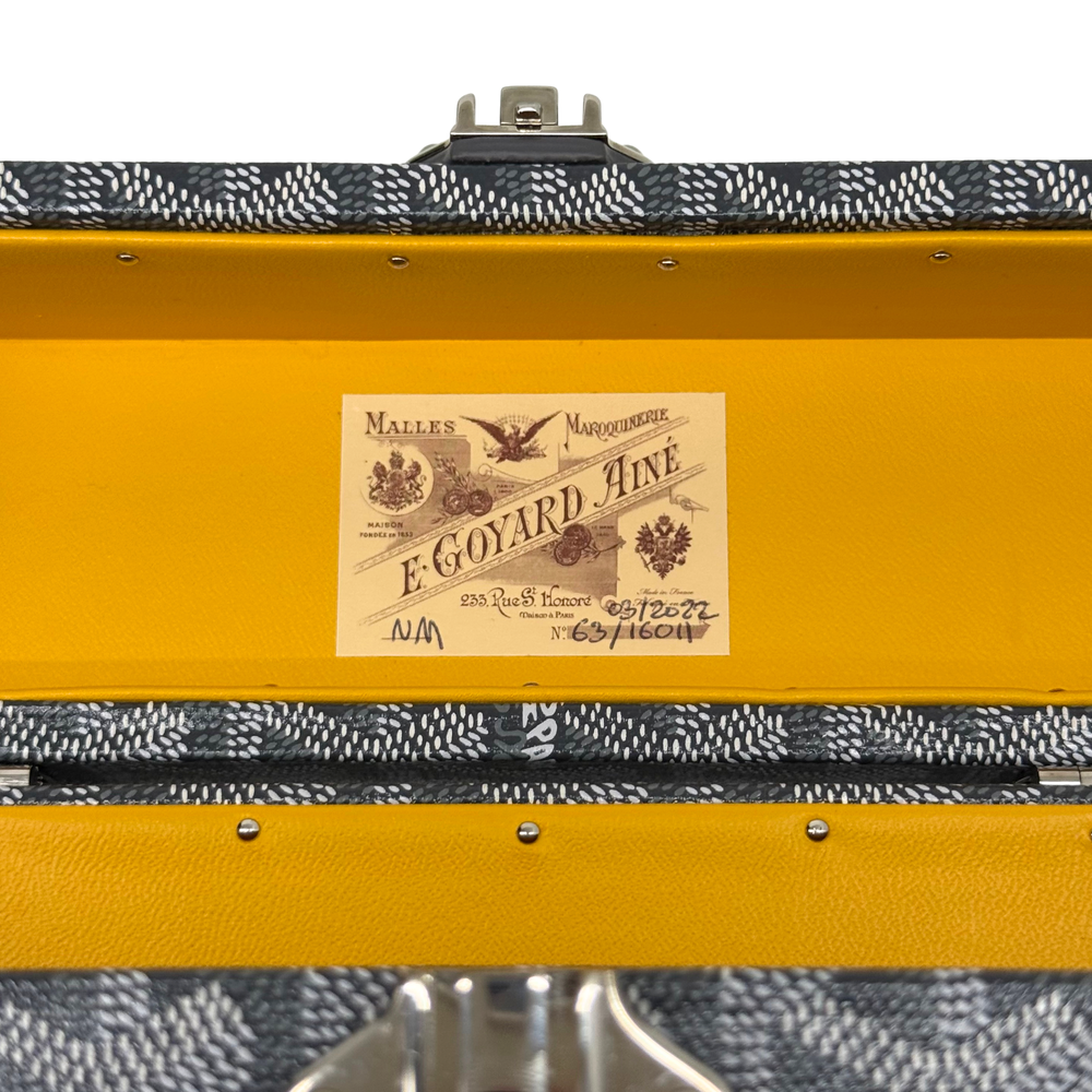 Goyard trunk top with metal latch and brand label on textured dark fabric