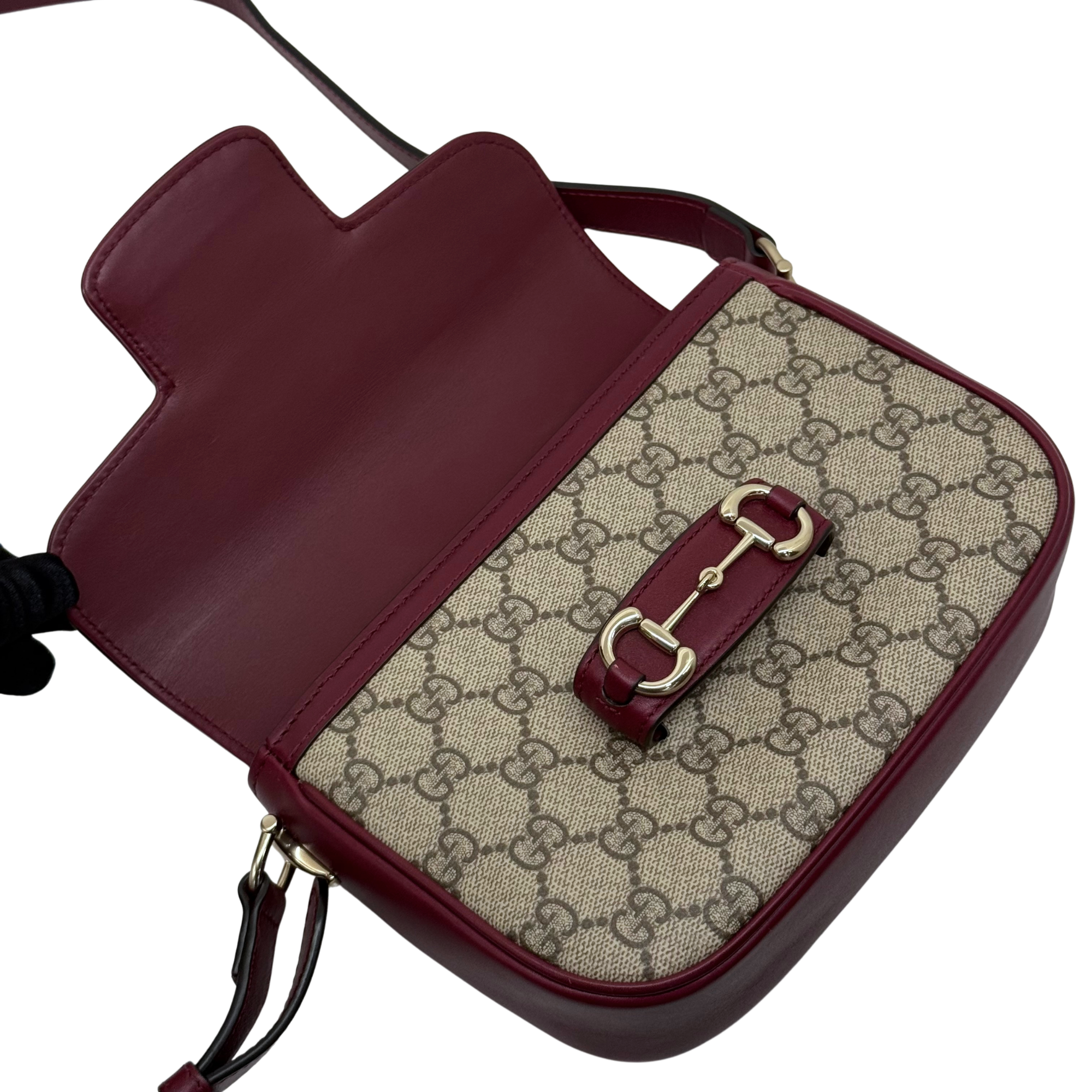 Gucci GG crossbody bag with open flap, burgundy leather lining, and gold buckle