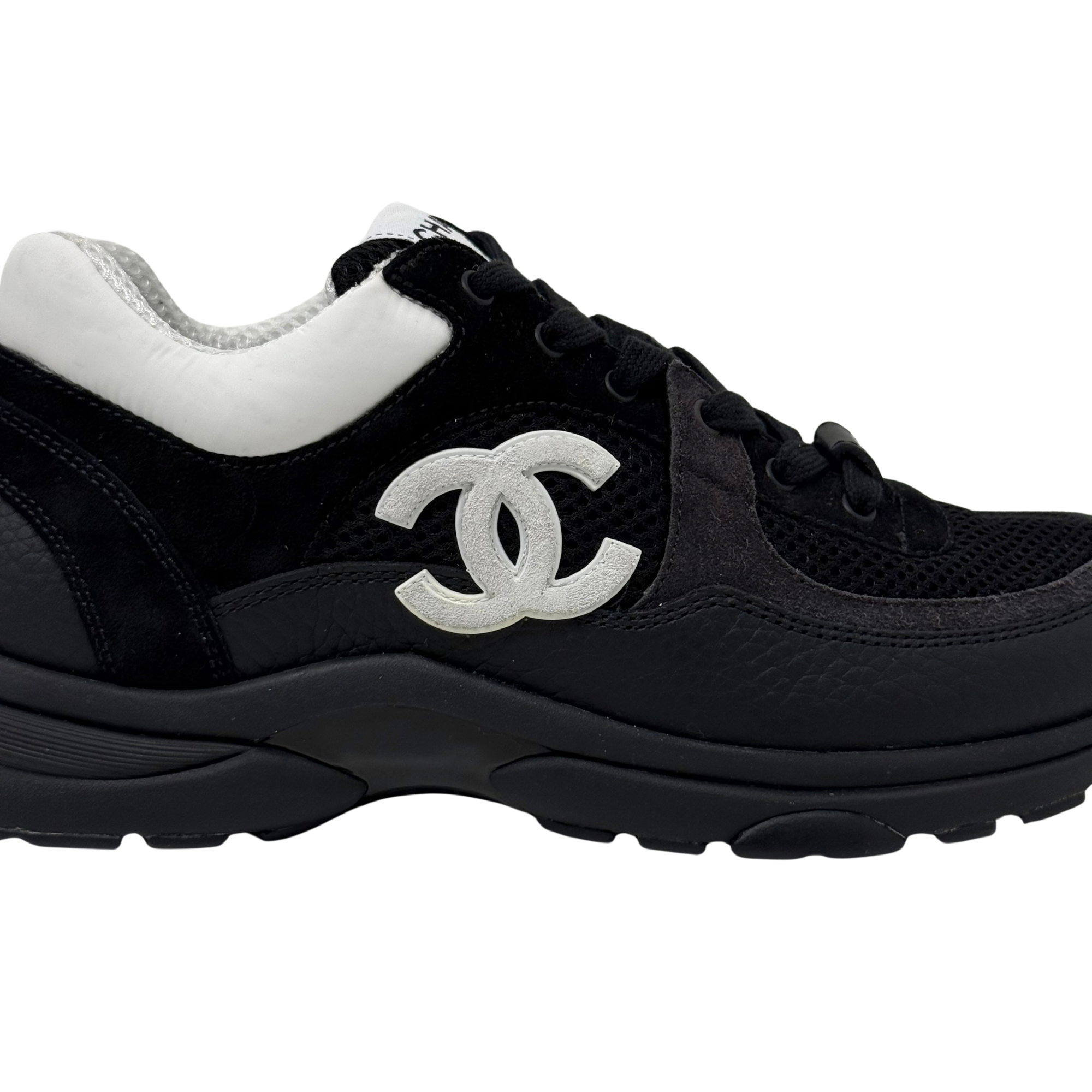 Black sneakers with large white Chanel CC logo on side and chunky outsole.