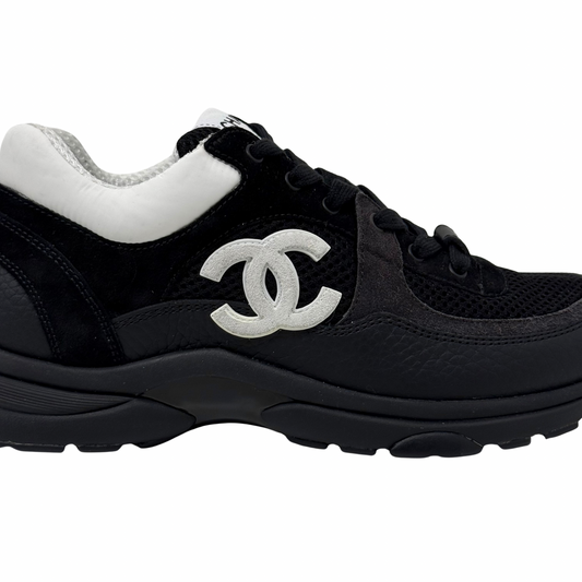 Black sneakers with large white Chanel CC logo on side and chunky outsole.