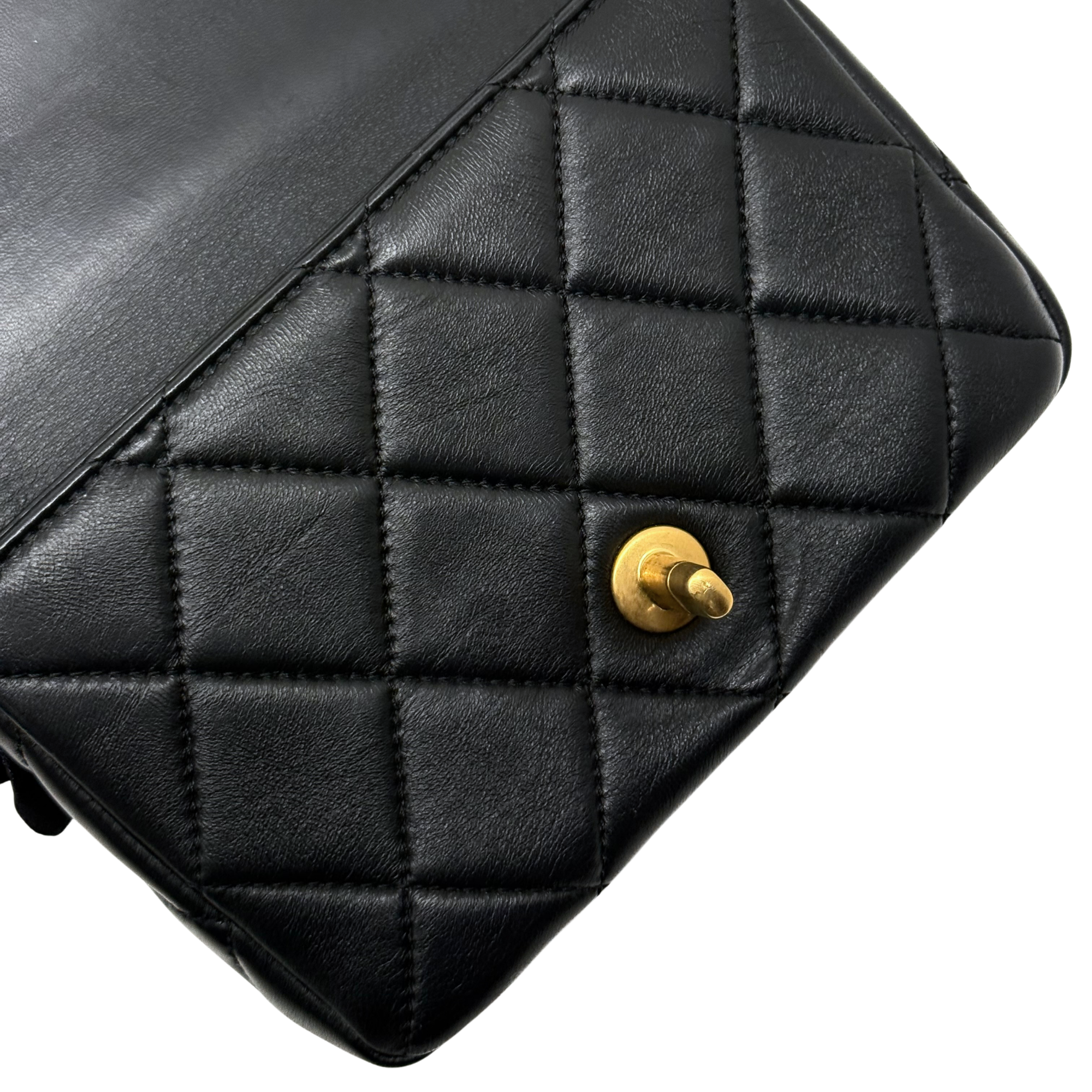 Black quilted leather flap with gold-tone button closure at center