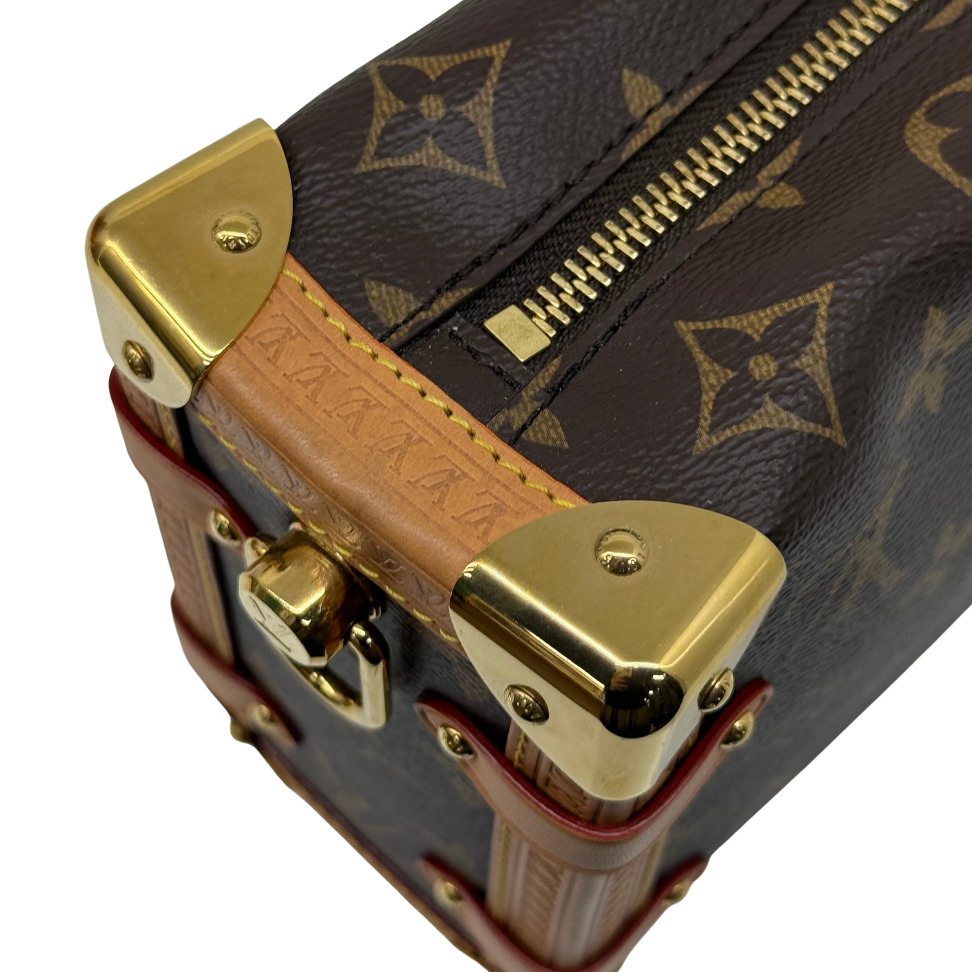 Close-up of monogram crossbody bag top edge with gold hardware and tan strap panel