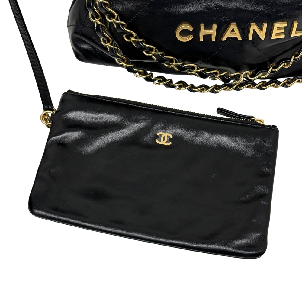Black leather crossbody clutch with gold Chanel logo and chain strap; zip closure