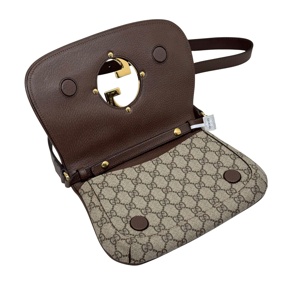 Gucci GG canvas crossbody bag with brown leather flap, gold G latch, and stud details