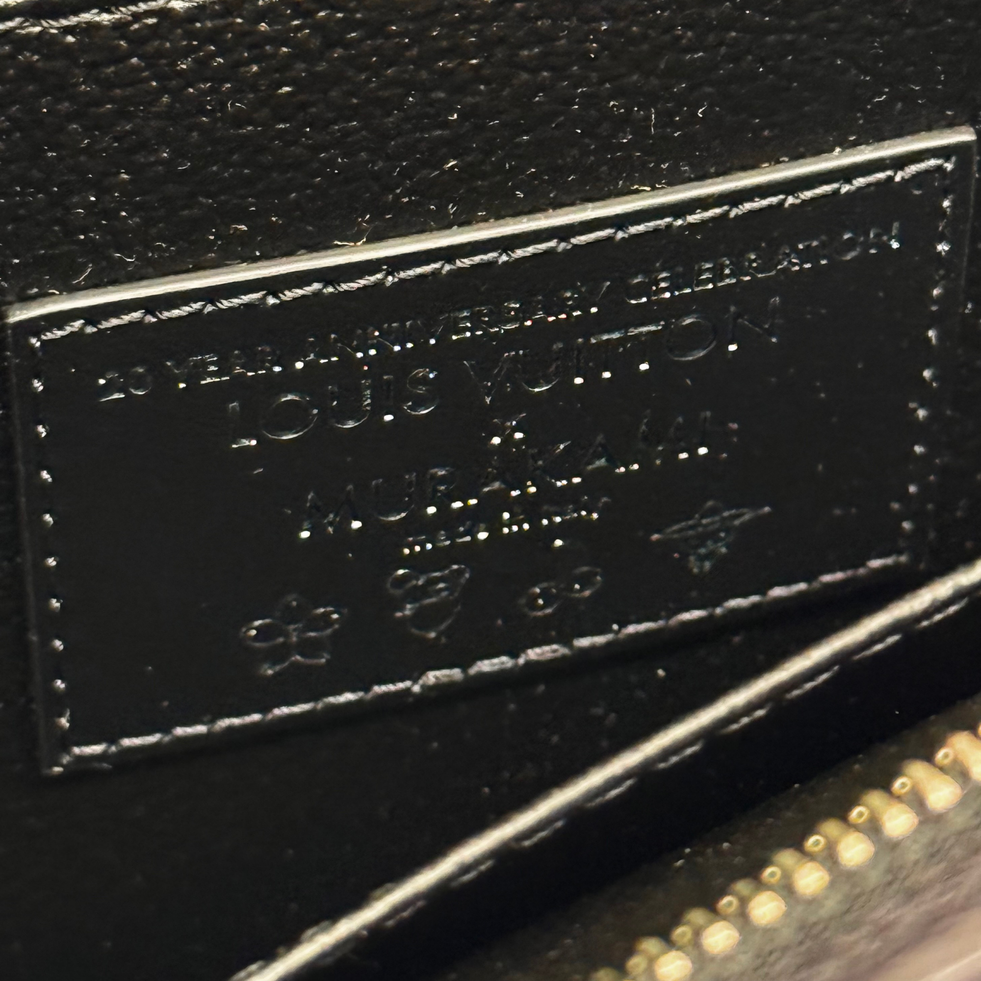 Louis Vuitton monogram leather pouch logo patch close-up with black fabric texture