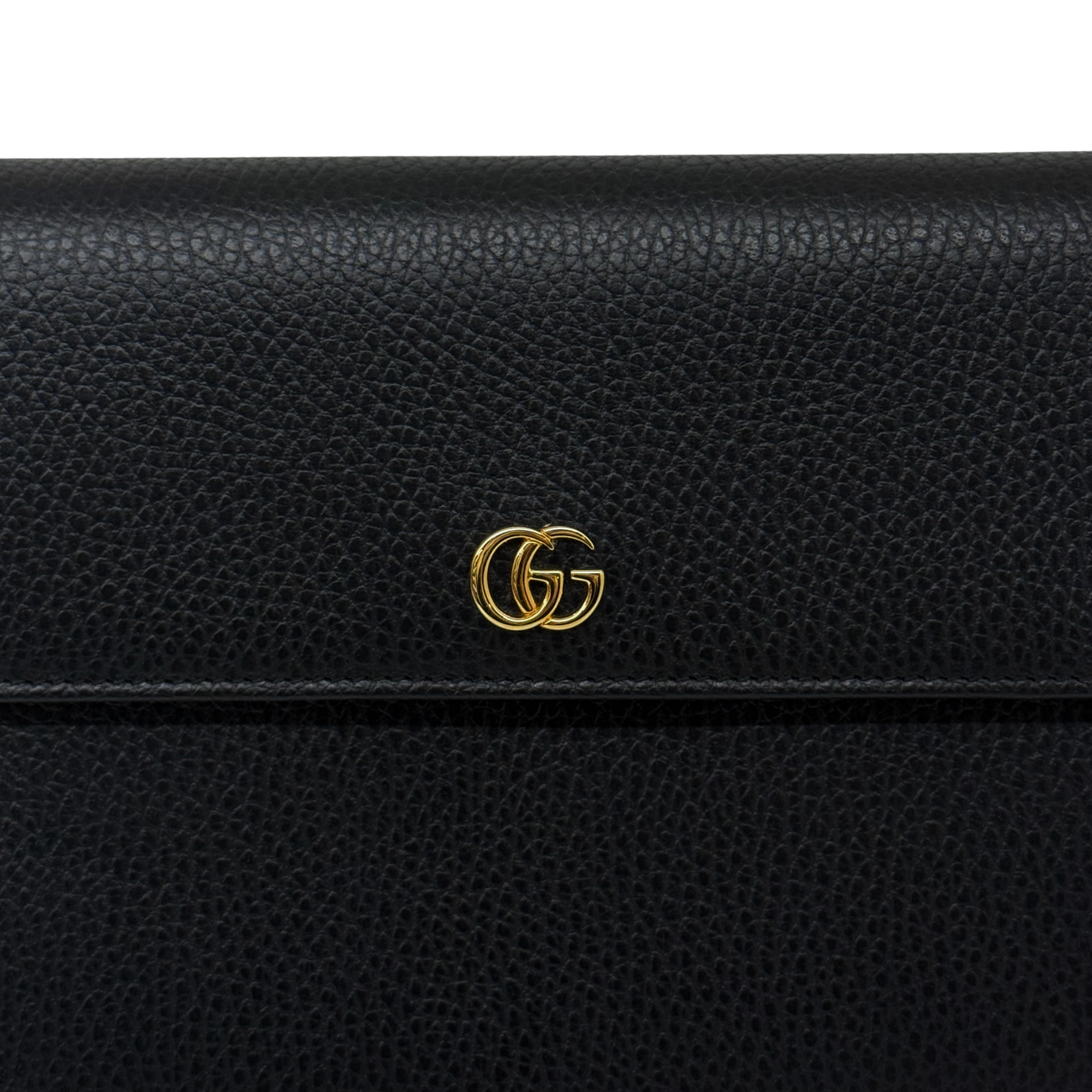 Black leather wallet close-up with gold double-G logo hardware on flap