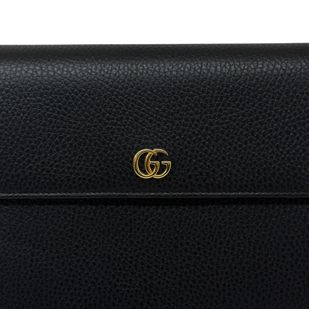 Black leather wallet close-up with gold double-G logo hardware on flap