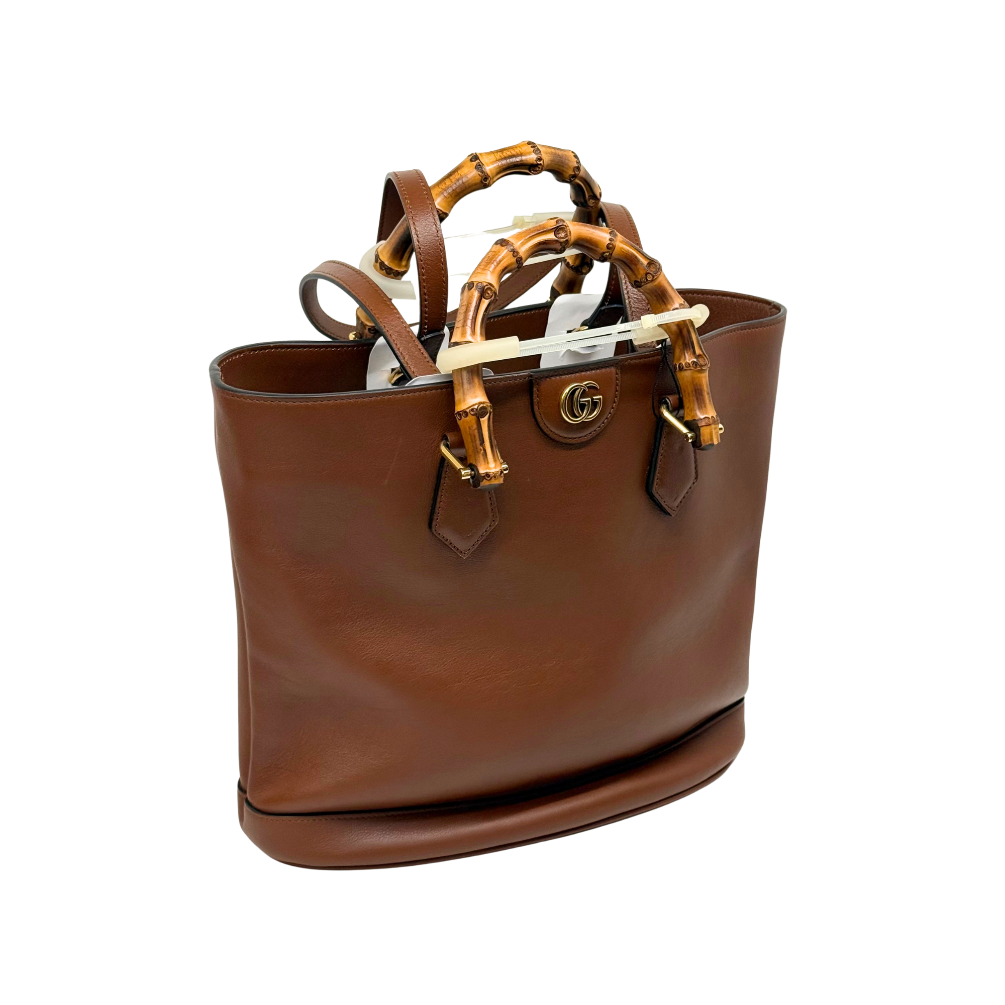 Brown leather Gucci tote with bamboo-style handle, front logo medallion, and zipper pull