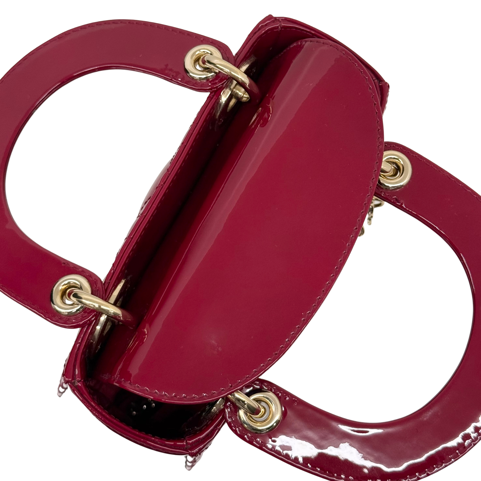 Red patent leather mini handbag with top handle, gold rings, and turn-lock closure