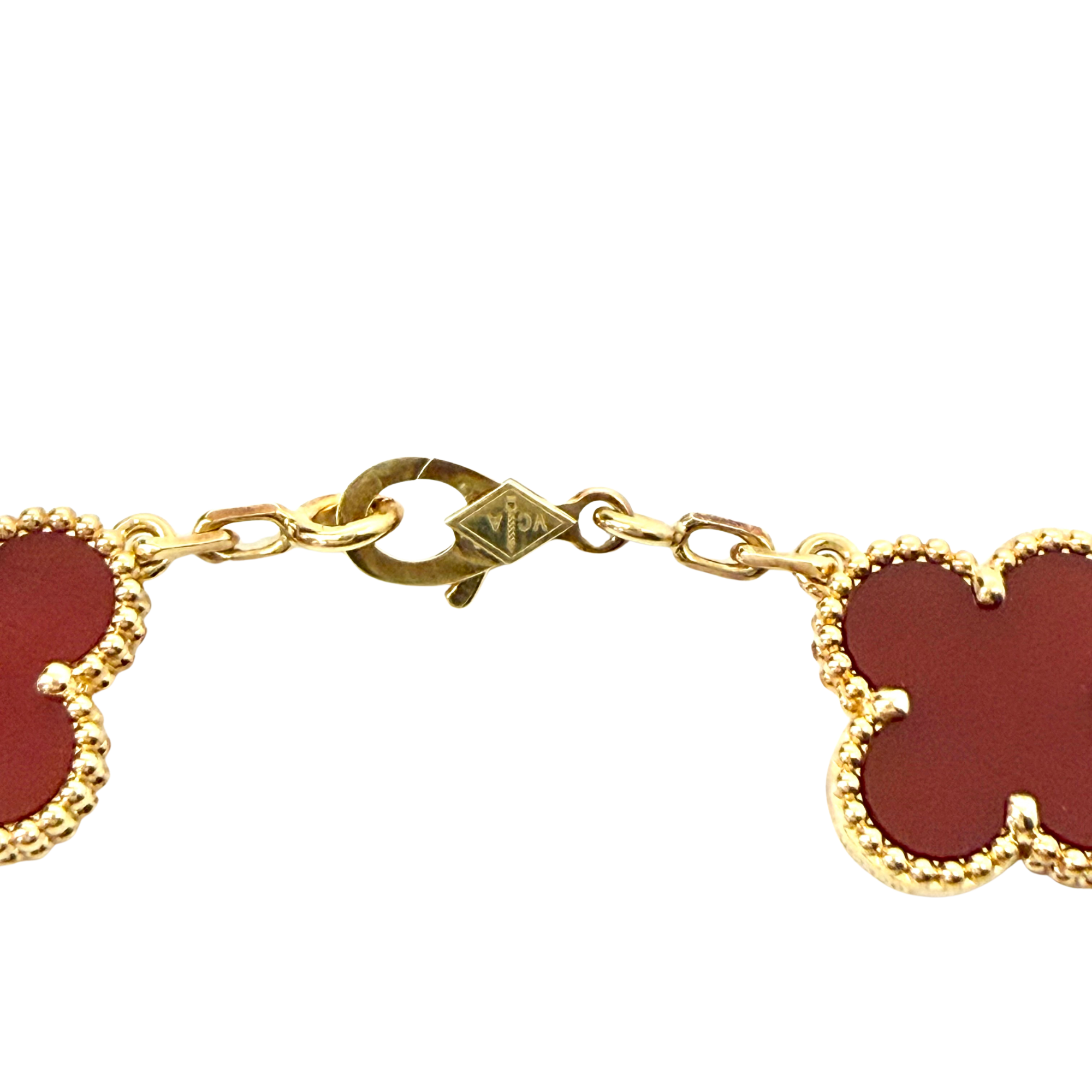 Gold bracelet clasp and link detail with red quatrefoil charm