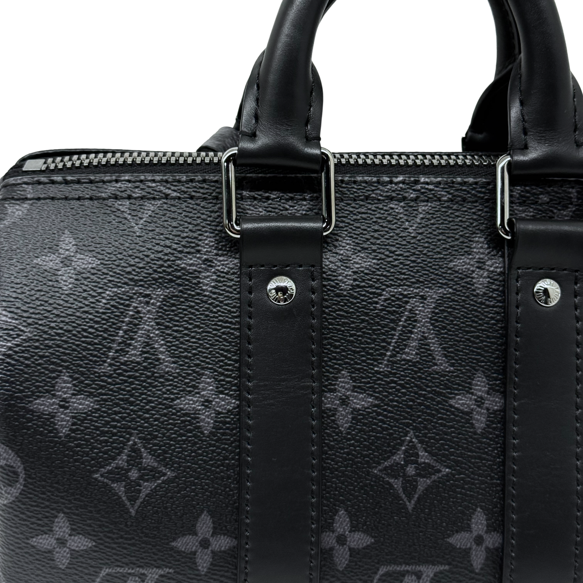 Black monogram handbag close-up of top handles and metal strap hardware